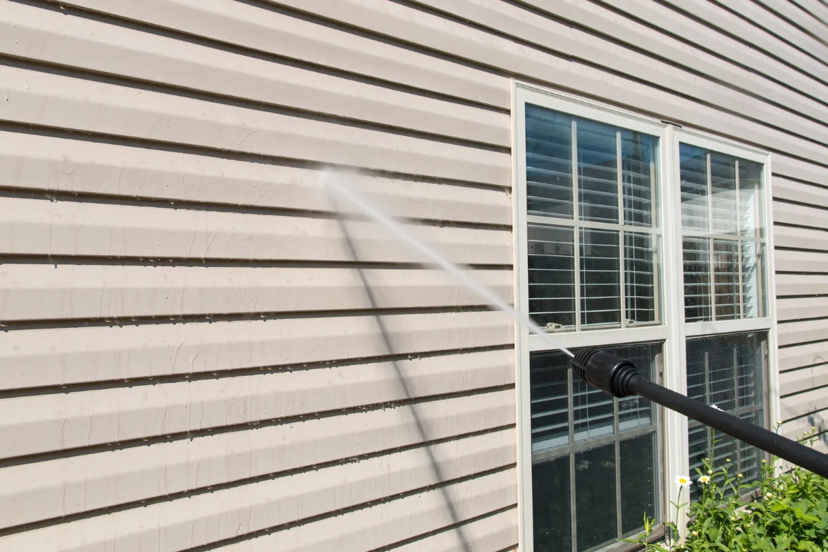 Pressure washer rinsing dirt and chalk from exterior siding.