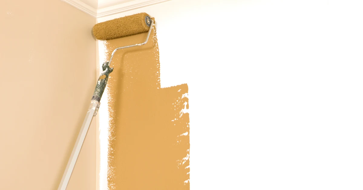 Paint roller applying a warm neutral finish to a clean interior wall.