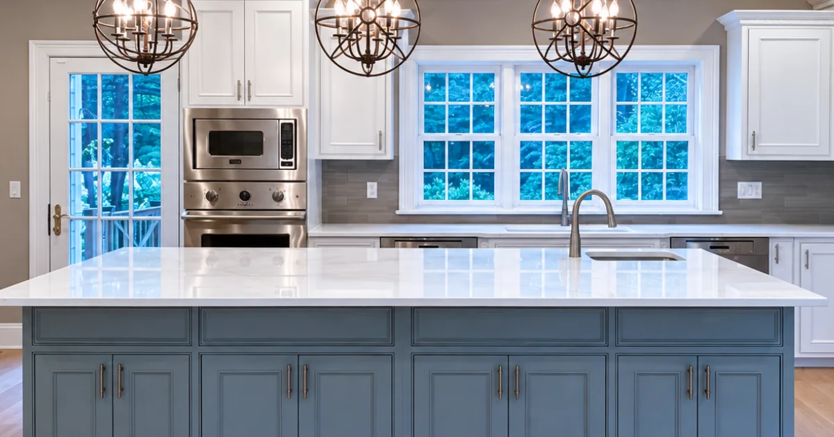 The same kitchen after refinishing, with white perimeter cabinets and a blue island.