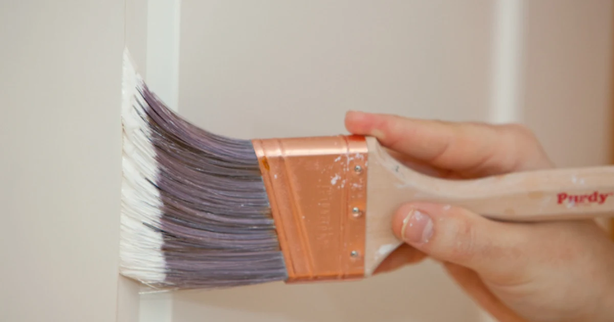Paint brush applying a clean finish along an interior edge.