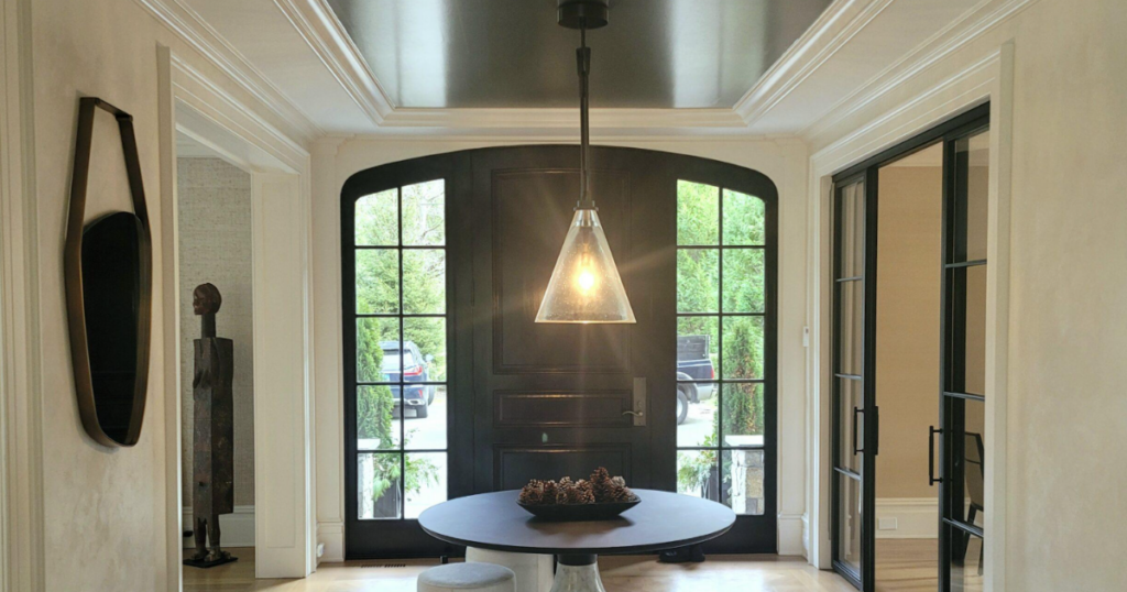 Dramatic black ceiling in a modern entryway with elegant molding and natural light.