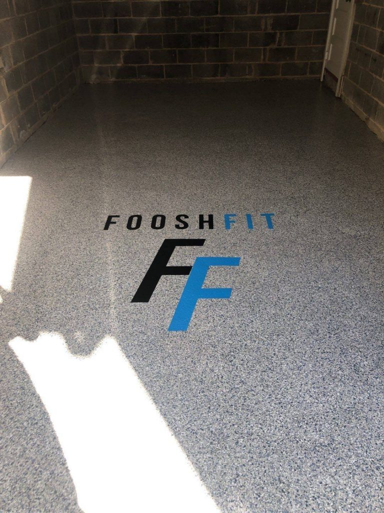 garage floor coating that is grey with a logo with blue and black F on floor