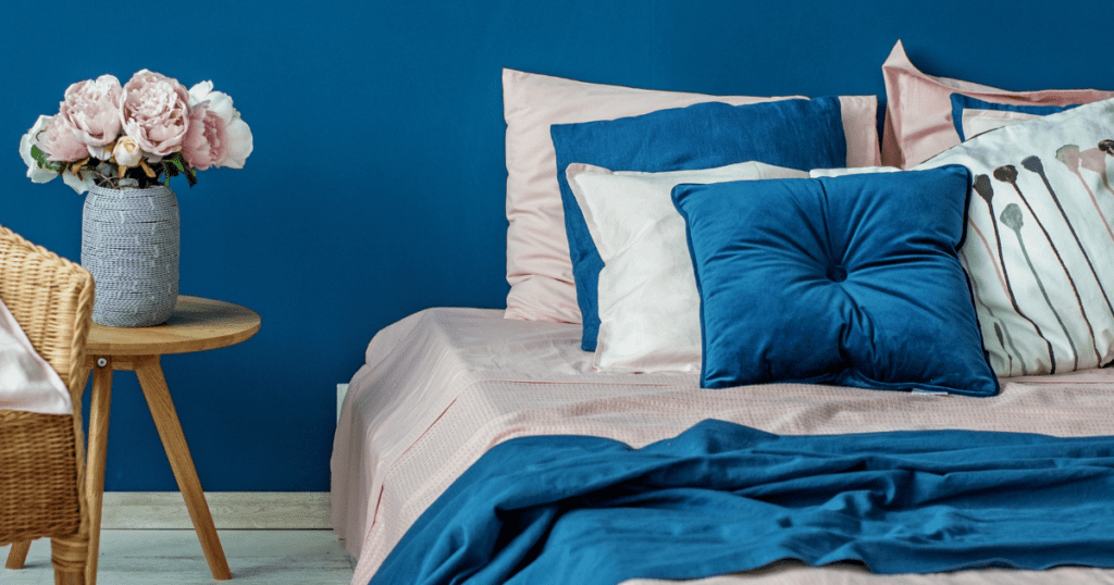 Cozy bedroom with blue walls, pink and blue bedding, and natural elements.