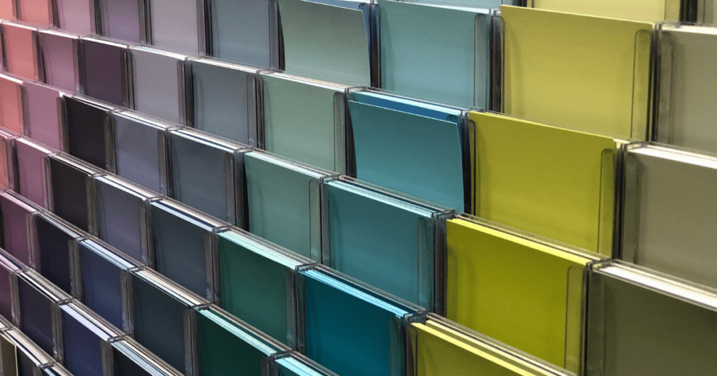 Array of colorful paint samples in a store, showcasing a gradient from pink to green.