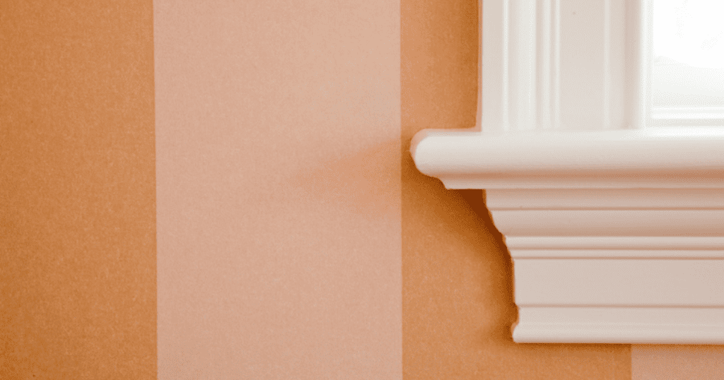 Close-up of beige and peach striped wall with white window trim.