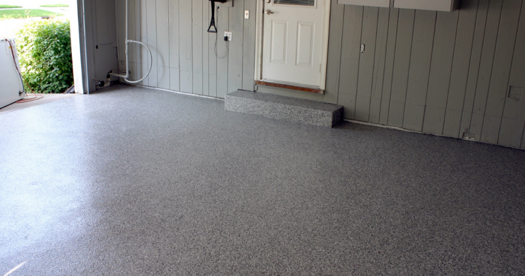 Garage interior with a gray polyurea-coated floor and a step covered in the same durable finish for a cohesive and polished design.