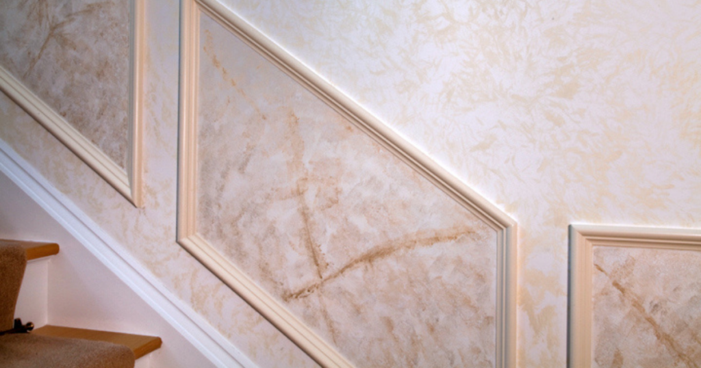 A staircase wall featuring faux painting techniques in warm peach tones, accented by decorative molding.