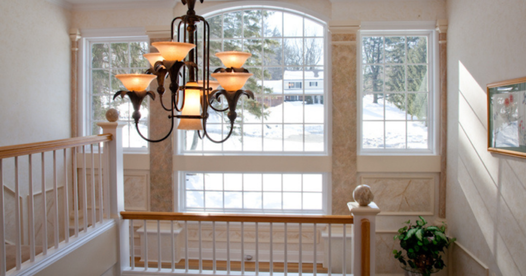 A bright staircase with large arched windows, natural light streaming in, and softly painted walls in a subtle textured finish.