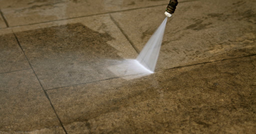 Close-up of a pressure washer cleaning a stone patio, removing dirt and grime for a refreshed finish.