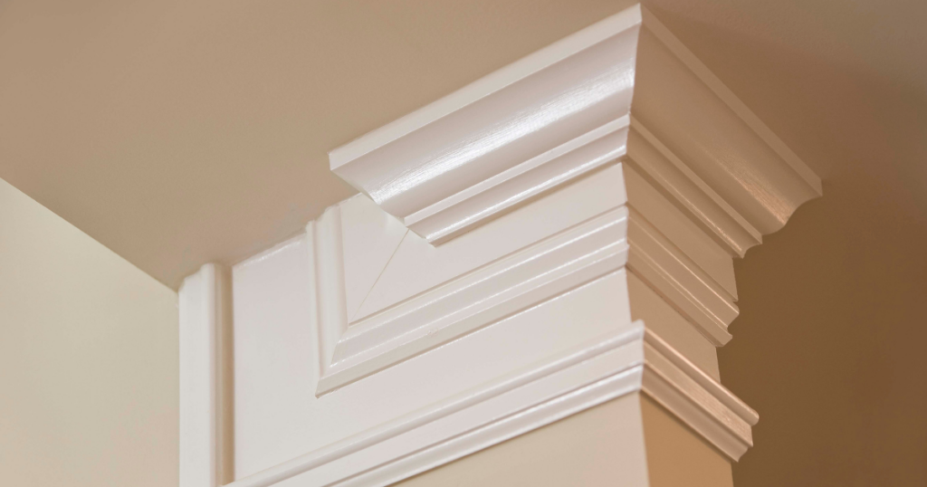 Close-up of white crown molding with intricate design and a smooth, glossy finish, showcasing precise craftsmanship.