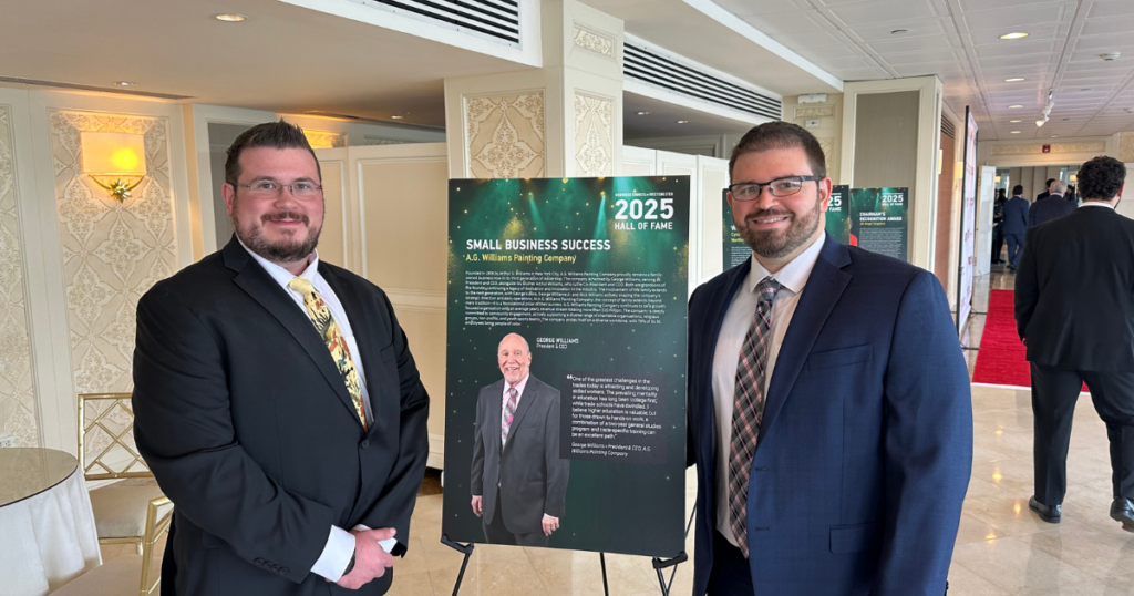 Nick Williams (left) and George Williams Jr. (right) from A.G. Williams Painting Company stand beside a display board showcasing their 2025 Hall of Fame recognition.